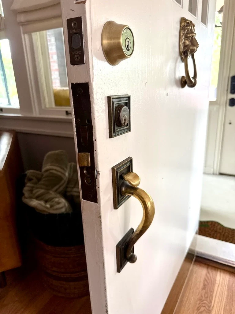 Original Corbin mortise lock and brass thumb-latch handle on the white Park Hill front door before repair
