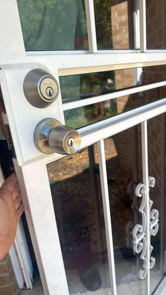 Residential locksmith case study showing a white barred security door with cylindrical deadbolt and knob, an older wood-door lockset, and a dark painted door with keys in its deadb