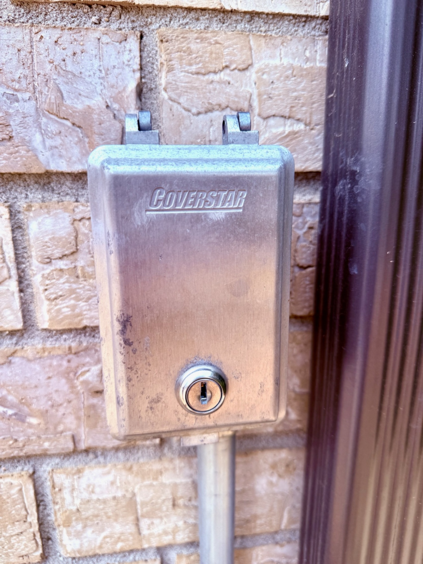 Coverstar-branded metal pool-cover lock enclosure with a keyed cylinder beside an exterior doorway in Broomfield
