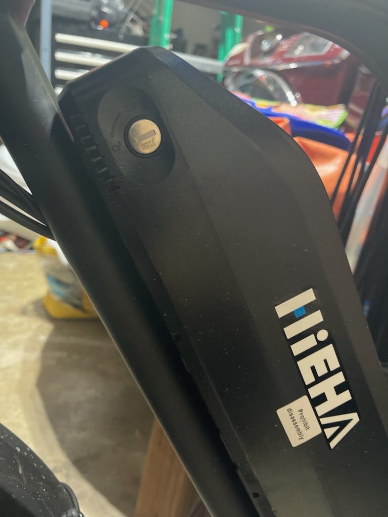 Close-up of a keyed cylinder integrated into the black battery housing of an electric bicycle in an indoor workshop. - view 2