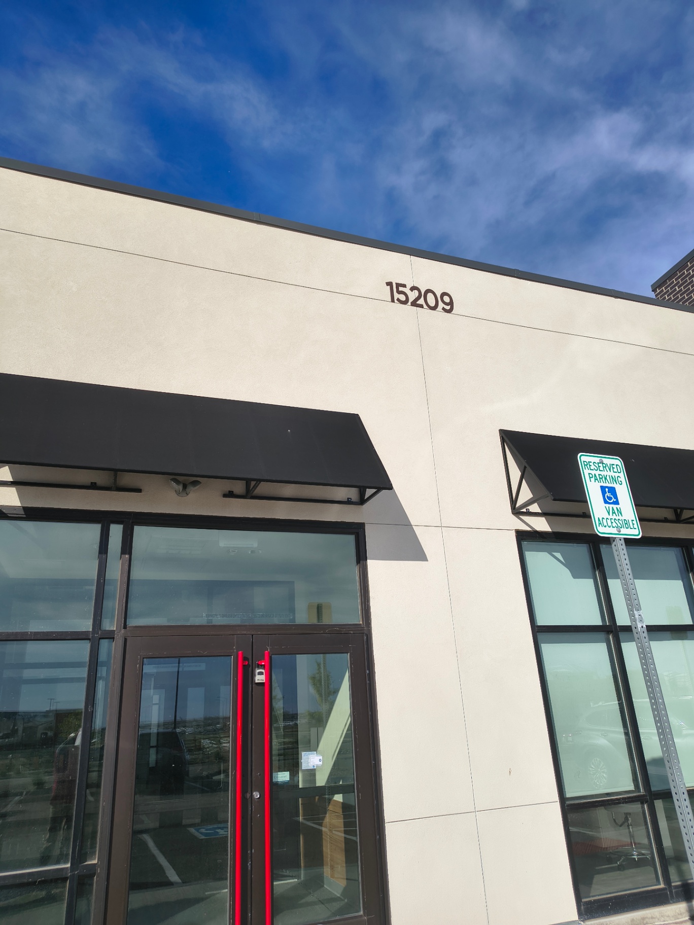 Black-framed commercial glass entrance in Arvada with pull handles and visible keyed lock cylinders - view 2