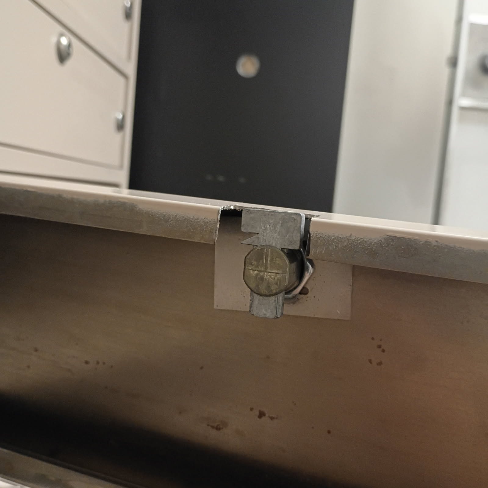 Close-up of a worn commercial cabinet or door with a chrome pull handle, round keyed cylinder, and exposed latch mechanism. - view 4