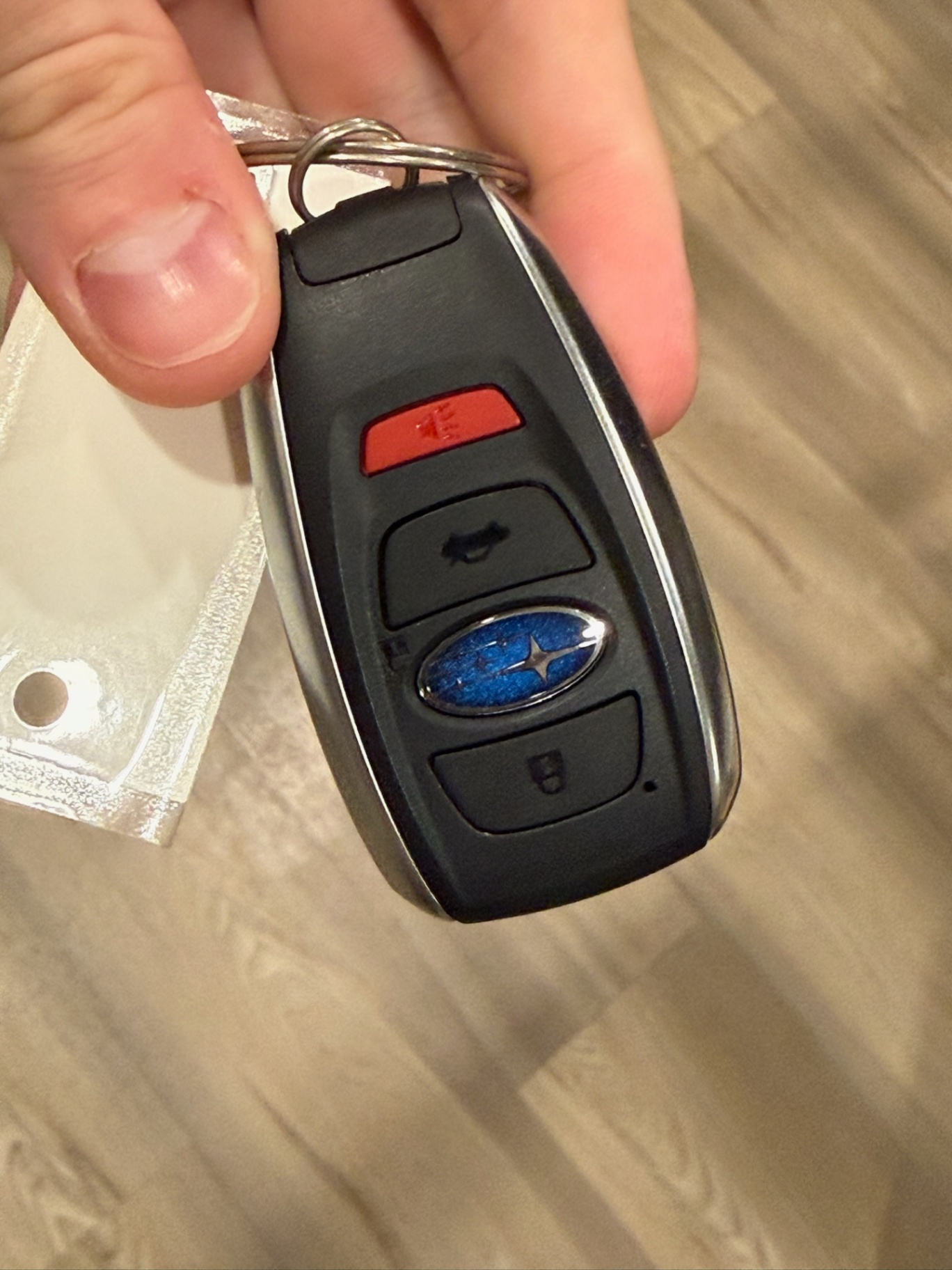 Close-up of an intact black vehicle remote key fob with multiple buttons, metal trim, an attached key ring, and a blue oval emblem.