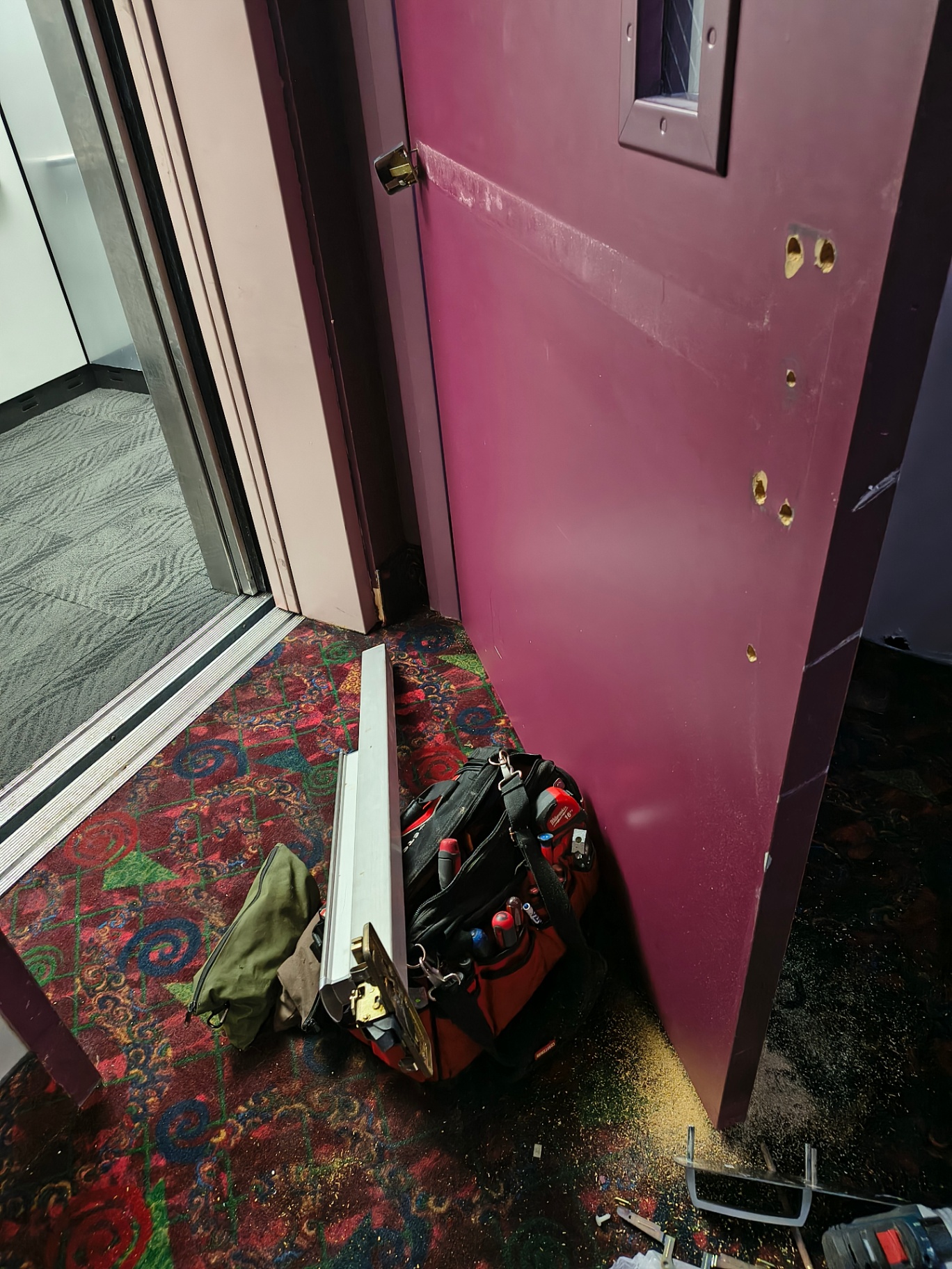 Burgundy commercial exit door in a Denver facility with a narrow wired-glass vision panel, panic bar, and brushed-metal lock escutcheon - view 6