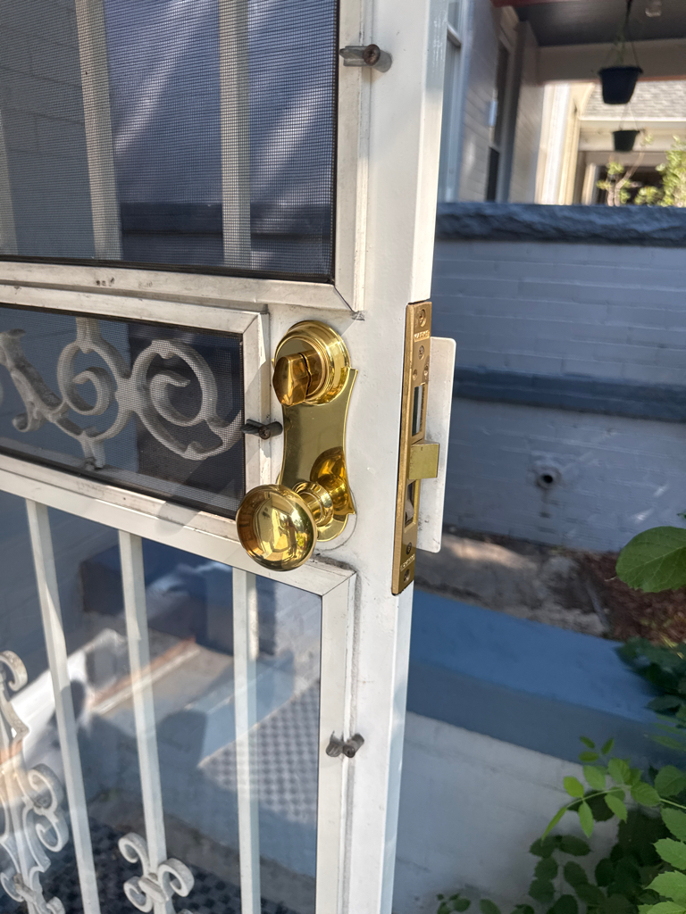 Brass keyed lock, knob, and mortise-style edge hardware on an older residential door in Denver - view 2