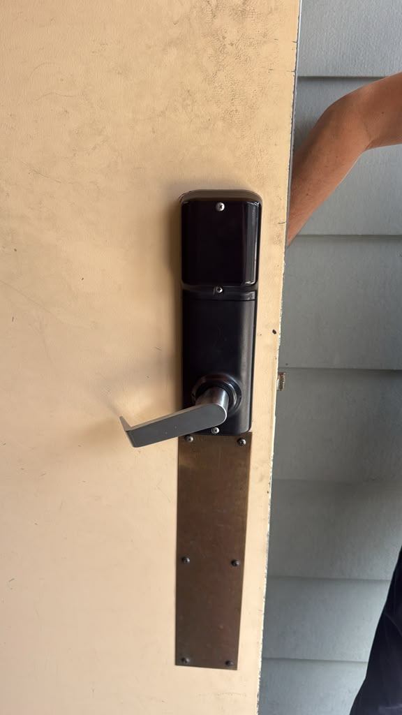 Mounted black commercial keypad lock with silver lever and long protective plate on a worn green door in Boulder - view 3