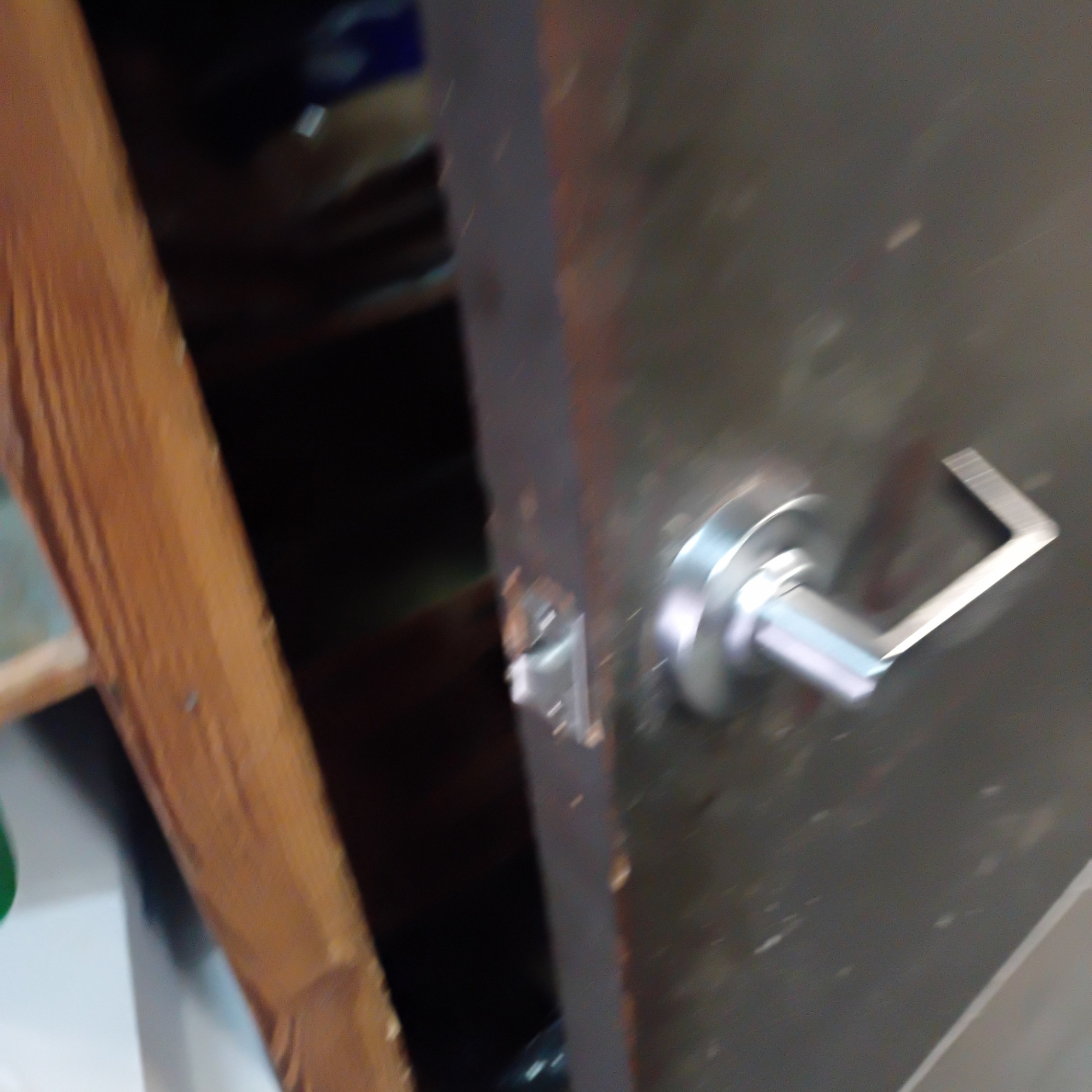 Interior commercial wooden doors in Arvada showing silver lever locks, a round knob with upper deadbolt, latch edges, and worn door surfaces. - view 2