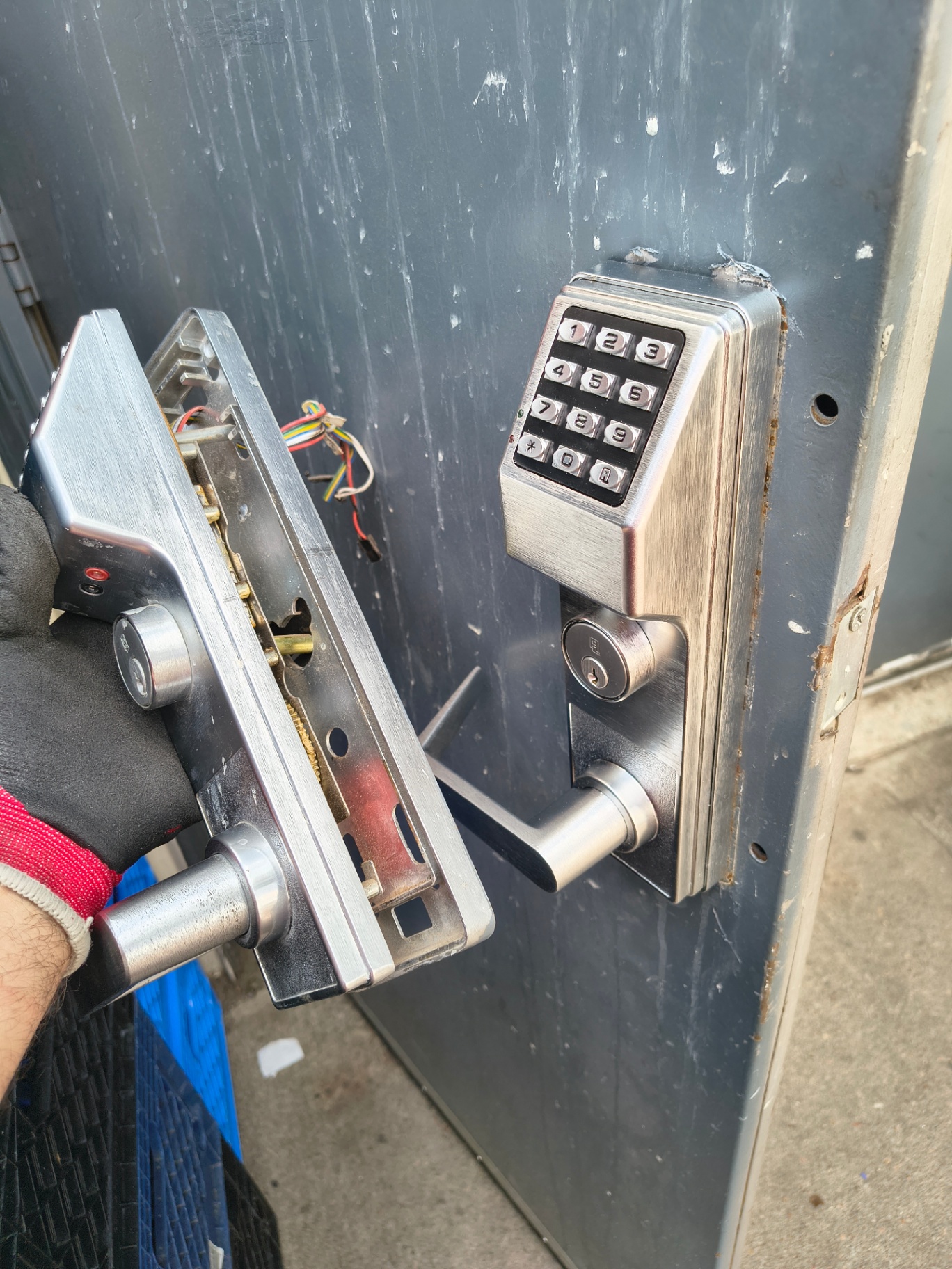 Commercial metal door with a silver numeric keypad lock, key cylinder, lever handle, rust, and exposed mounting holes. - view 7