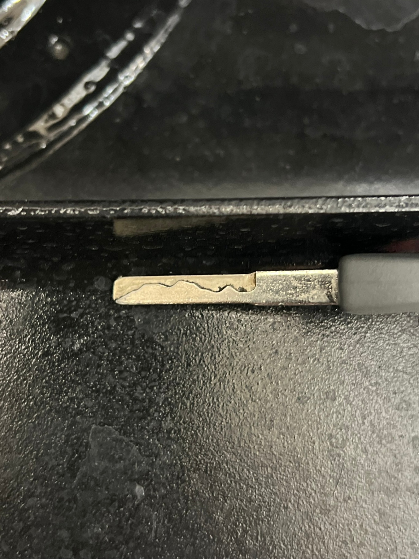 Close-up of a black vehicle remote key fob with lock, unlock, and panic buttons beside a Ford-branded mechanical key with visible blade cuts. - view 2