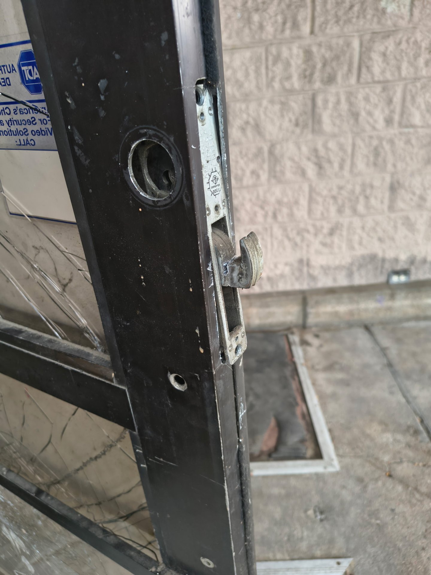Gloved locksmith holds a removed mortise lock assembly beside a commercial door with a keyed cylinder and keys visible. - view 3