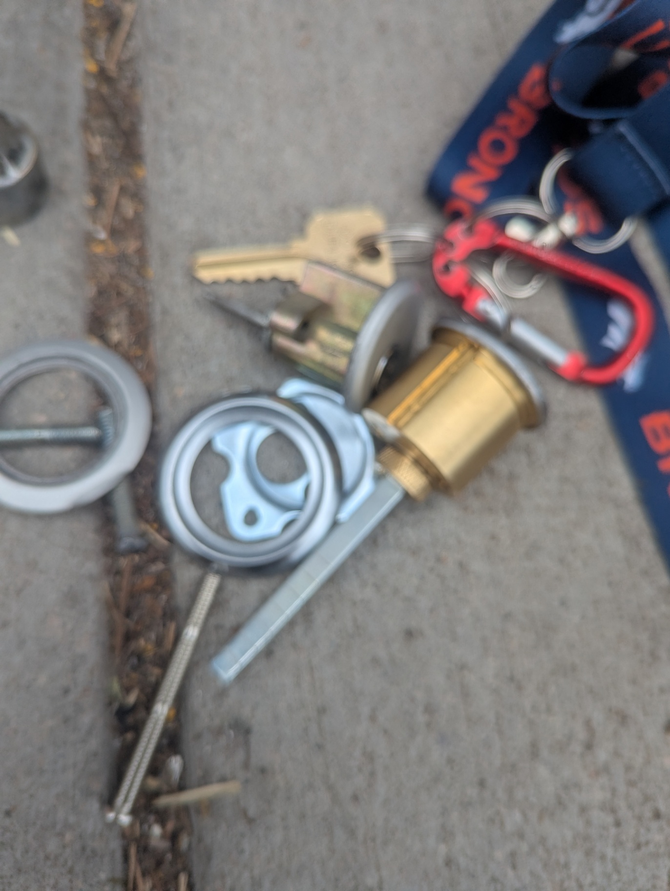 Locksmith handling a rim-cylinder component and keys at a Denver commercial glass storefront entrance with panic-bar hardware visible nearby.