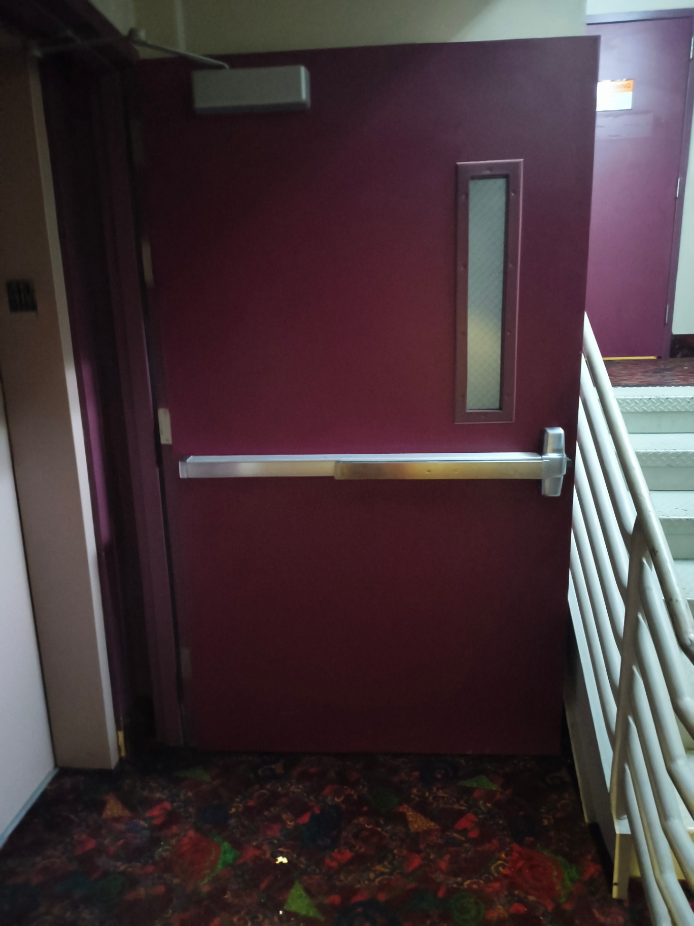 Burgundy commercial exit door in a Denver facility with a narrow wired-glass vision panel, panic bar, and brushed-metal lock escutcheon - view 5