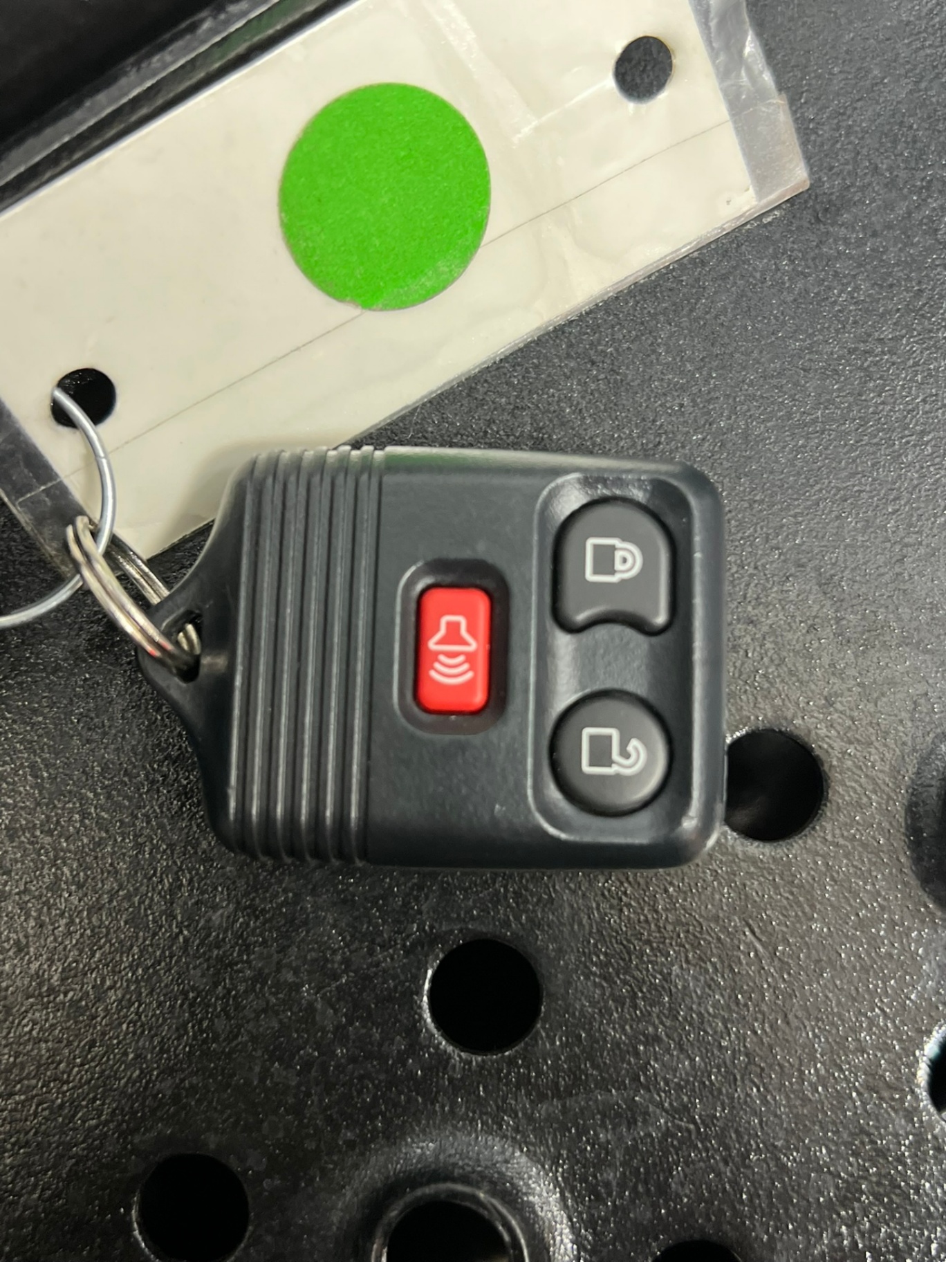 Close-up of a black vehicle remote key fob with lock, unlock, and panic buttons beside a Ford-branded mechanical key with visible blade cuts.