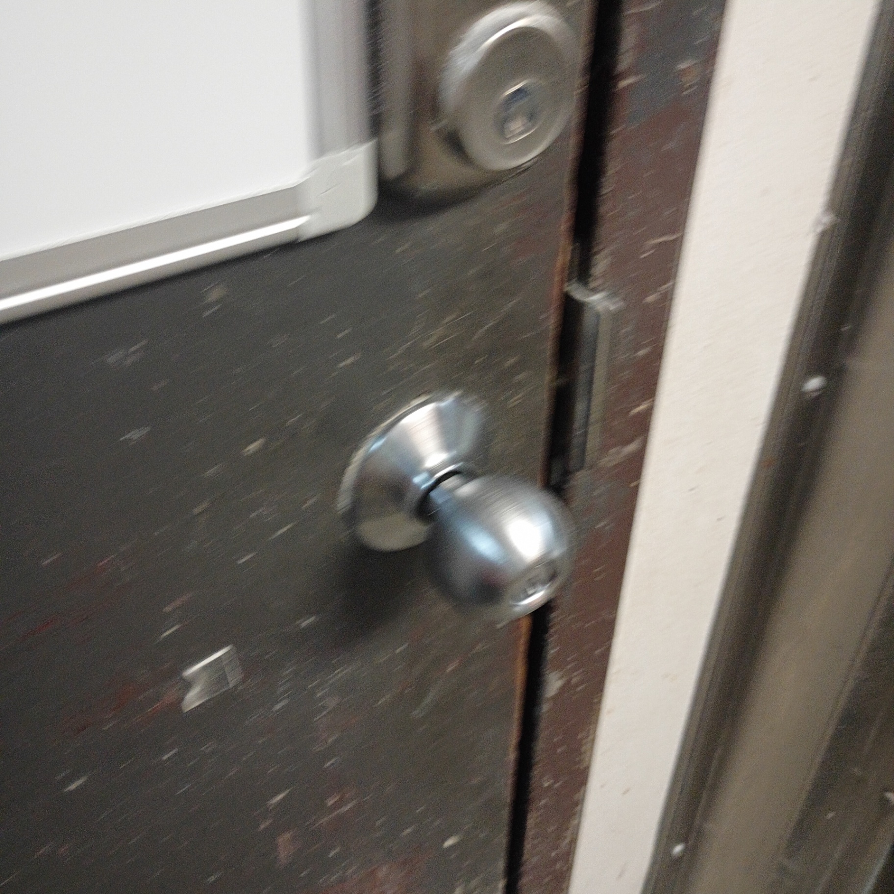 Interior commercial wooden doors in Arvada showing silver lever locks, a round knob with upper deadbolt, latch edges, and worn door surfaces. - view 3