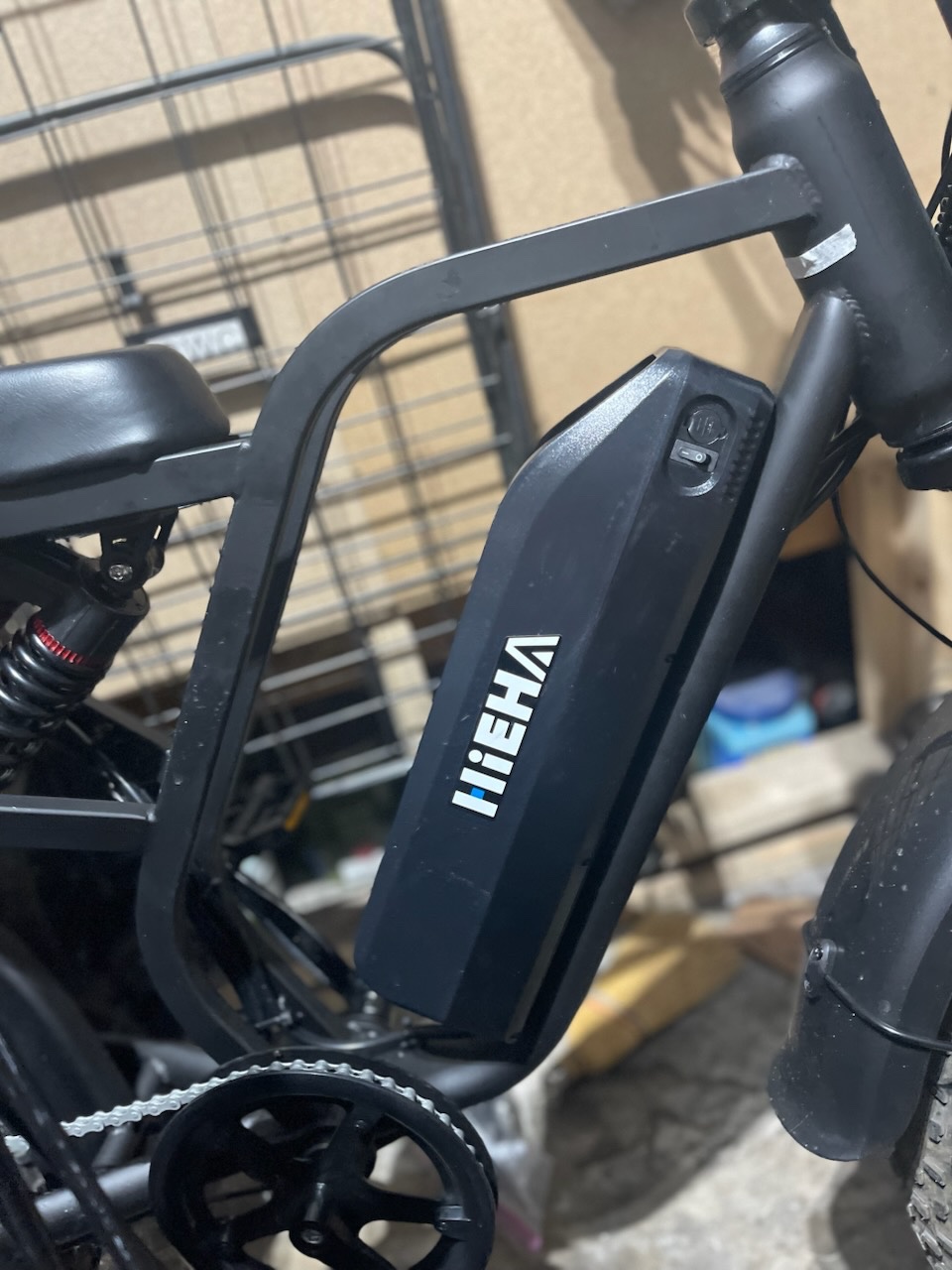 Close-up of a keyed cylinder integrated into the black battery housing of an electric bicycle in an indoor workshop. - view 3