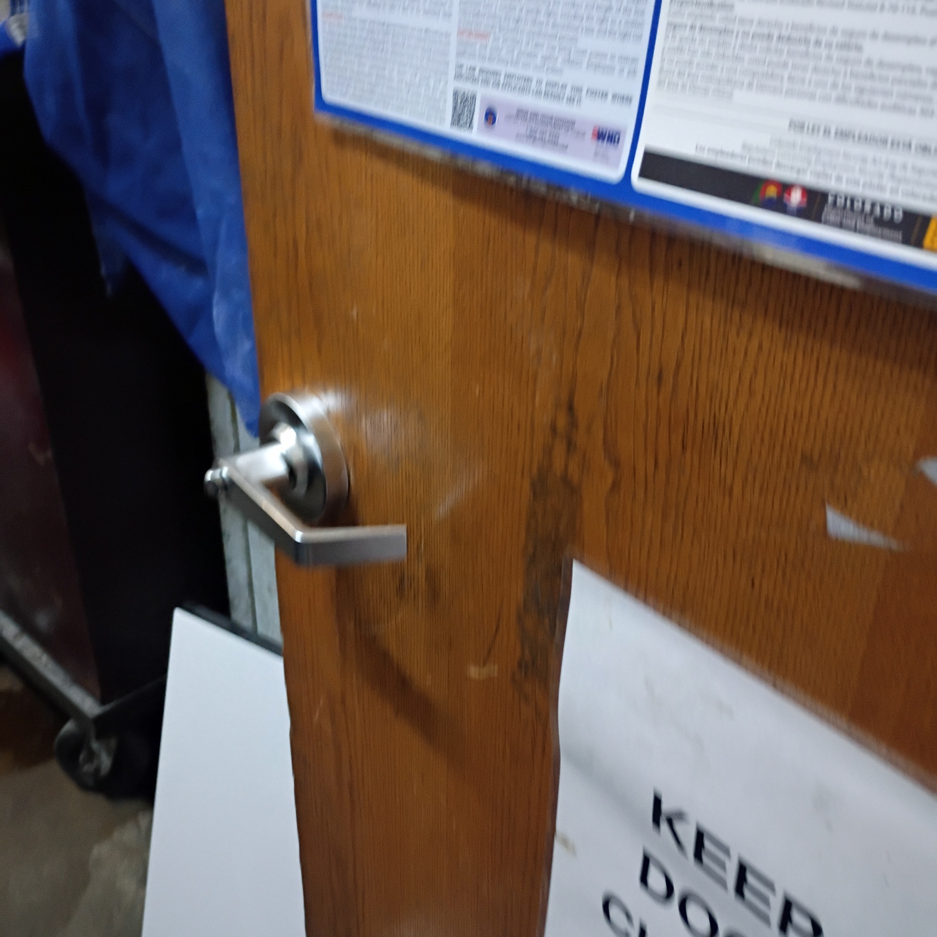 Interior commercial wooden doors in Arvada showing silver lever locks, a round knob with upper deadbolt, latch edges, and worn door surfaces.