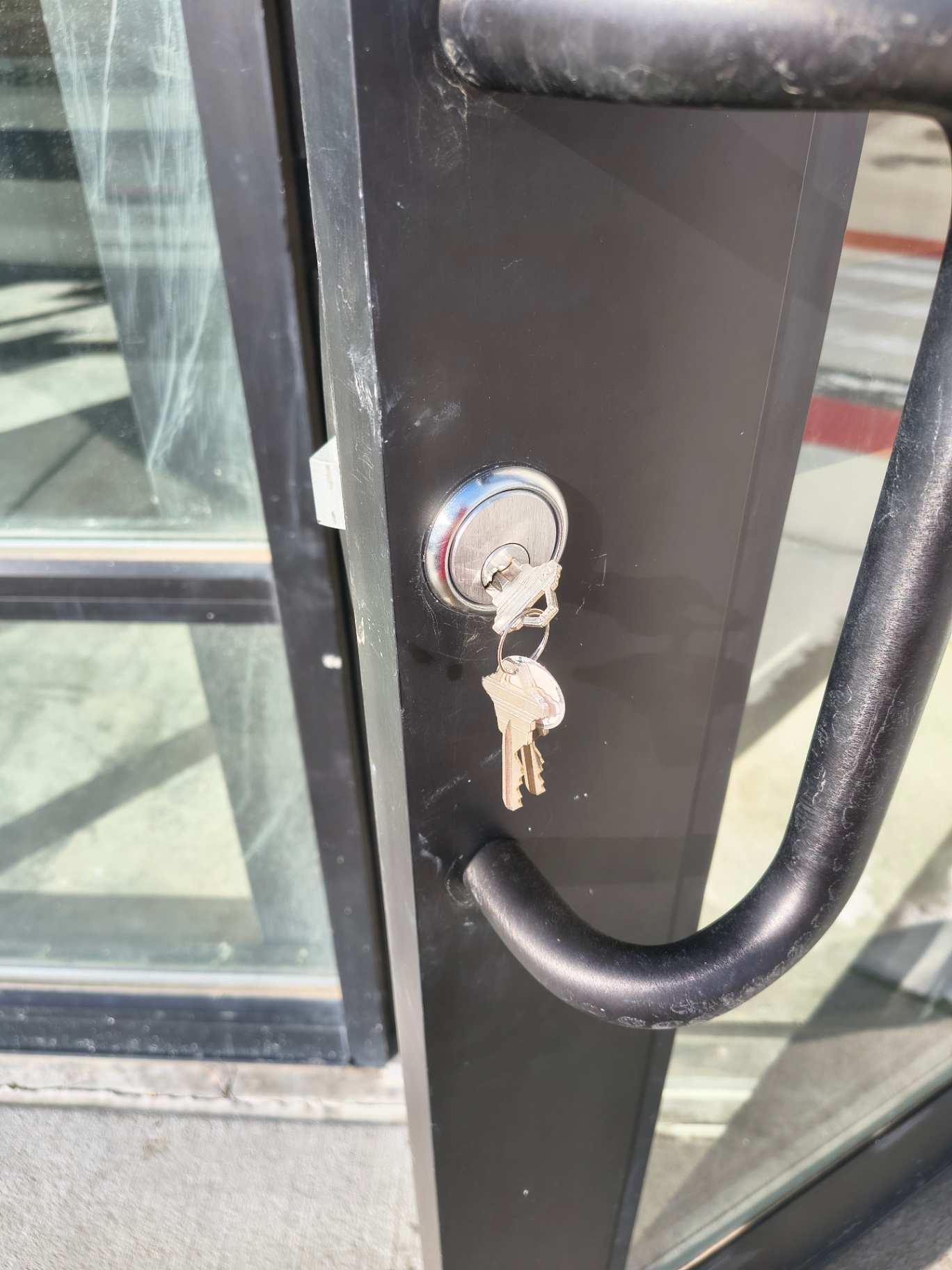 Black-framed commercial glass entrance in Arvada with pull handles and visible keyed lock cylinders - view 4