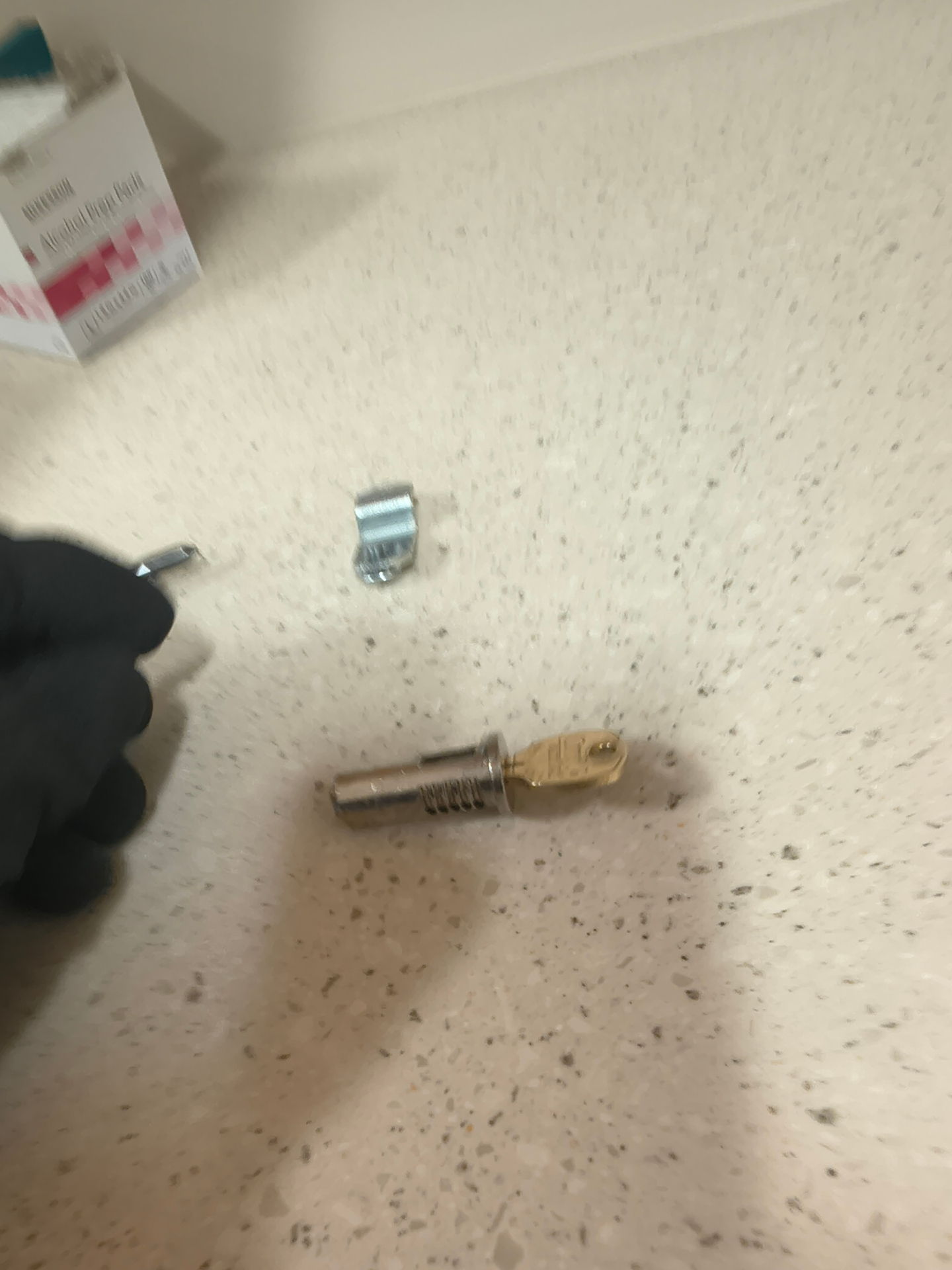 Exposed cylindrical cam lock with brass-colored key on a wood-finish interior cupboard beside an electronic access device in Westminster - view 2